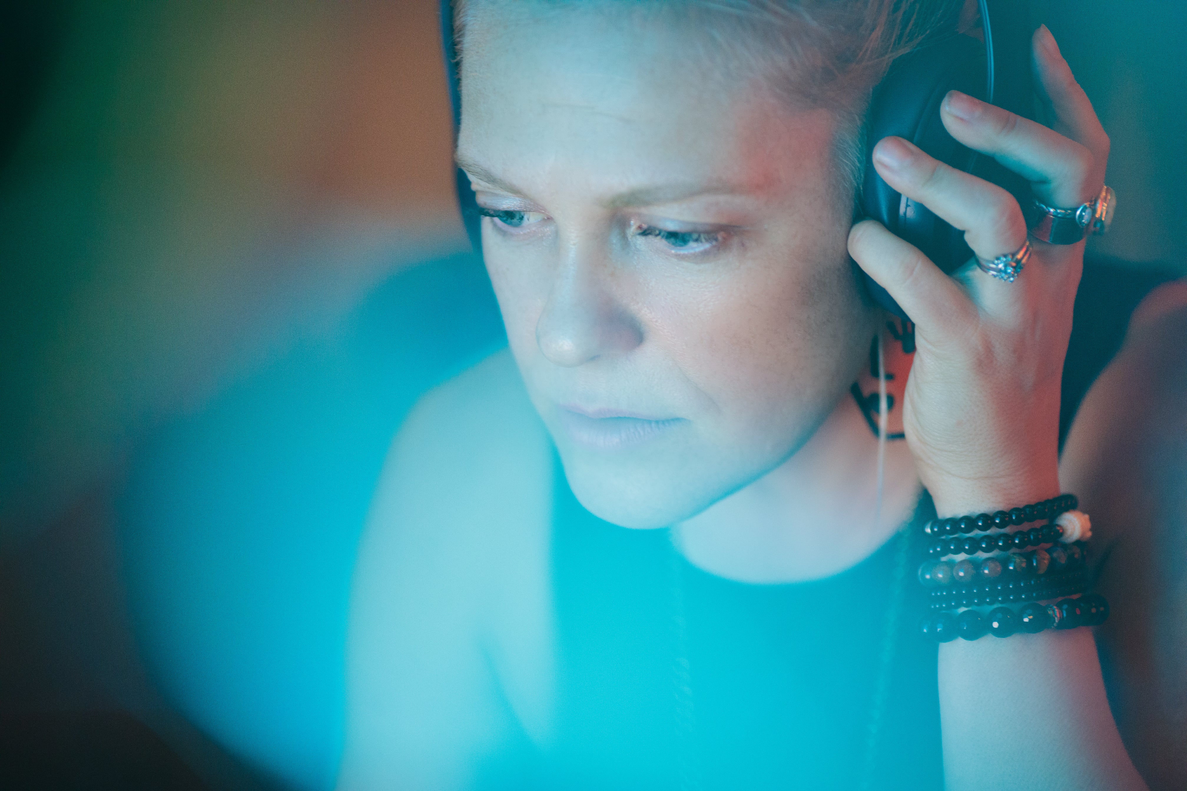 Woman holding headphones to her ear, staring at laptop screen