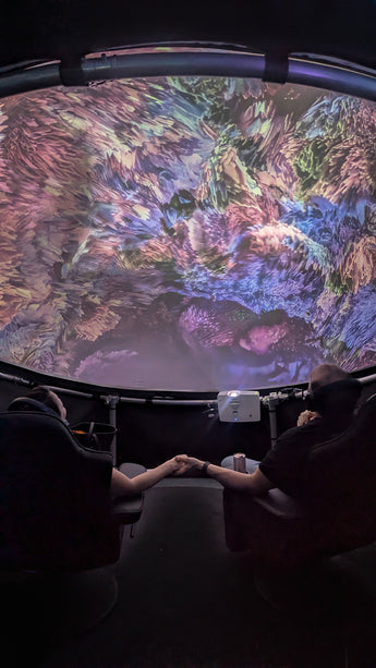 Two people holding hands and sitting in a Setl immersive projection dome