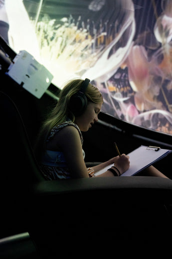 Child writing on a clipboard while sitting in a Setl immersive projection dome