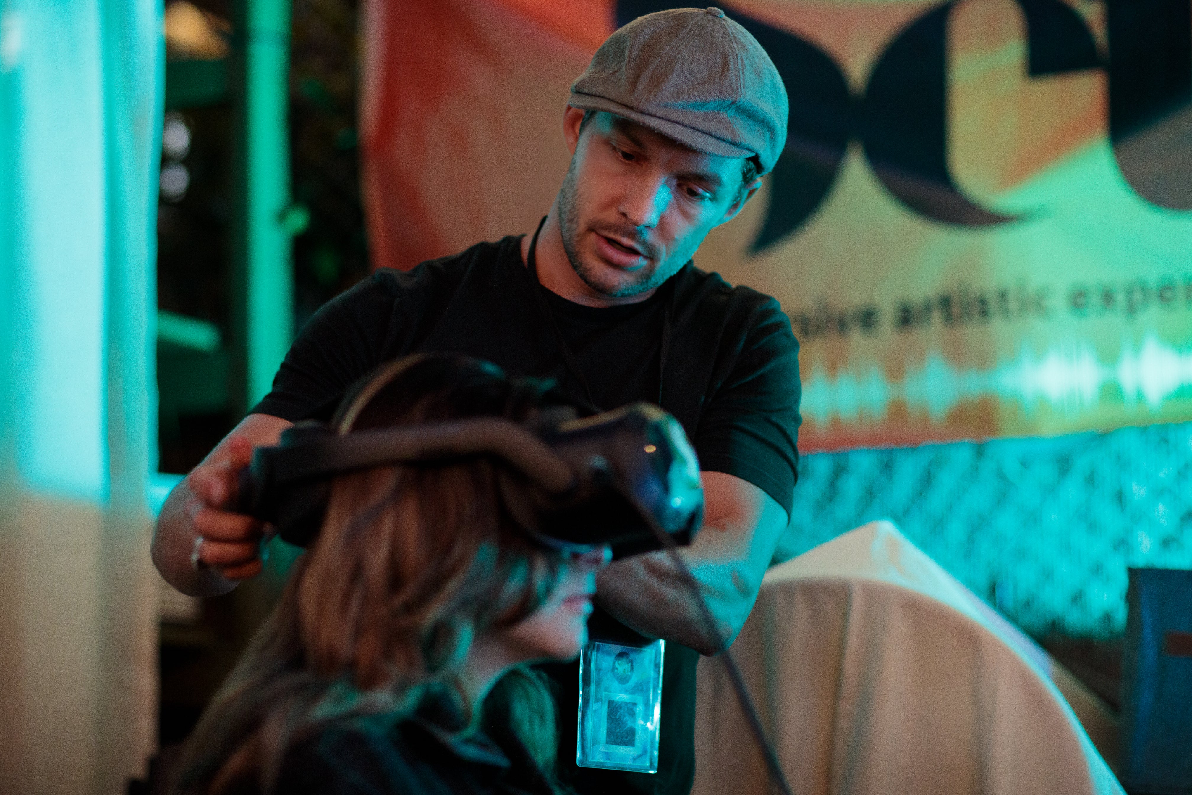 Seated woman wearing Setl virtual reality headset, man standing behind her adjusting the headset