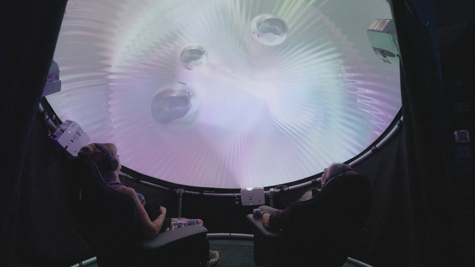 Two adults seated in an immersive projection dome